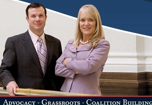 Two professionals pose in a hallway for an advocacy banner; bottom line reads ‘Advocacy - Grassroots - Coalition Building’.