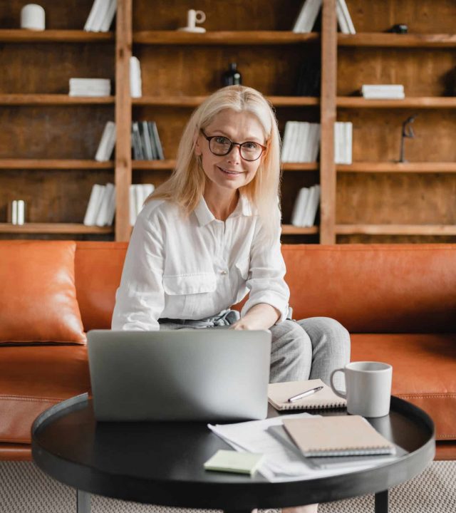 Successful caucasian mature middle-aged businesswoman CEO freelancer leader teacher working on laptop in home office, surfing net, watching webinars, e-learning, e-banking online