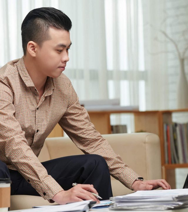 Young Asian businessman working with documents from home